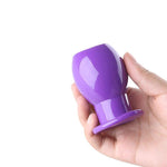 plug anal de silicona morado con un tunel en una mano
